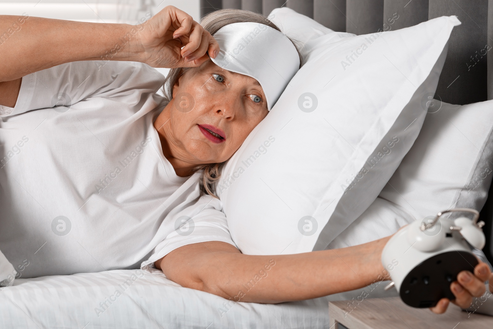 Photo of Overslept woman with alarm clock in bed at home