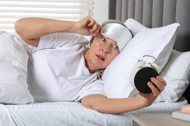 Photo of Overslept woman with alarm clock in bed at home