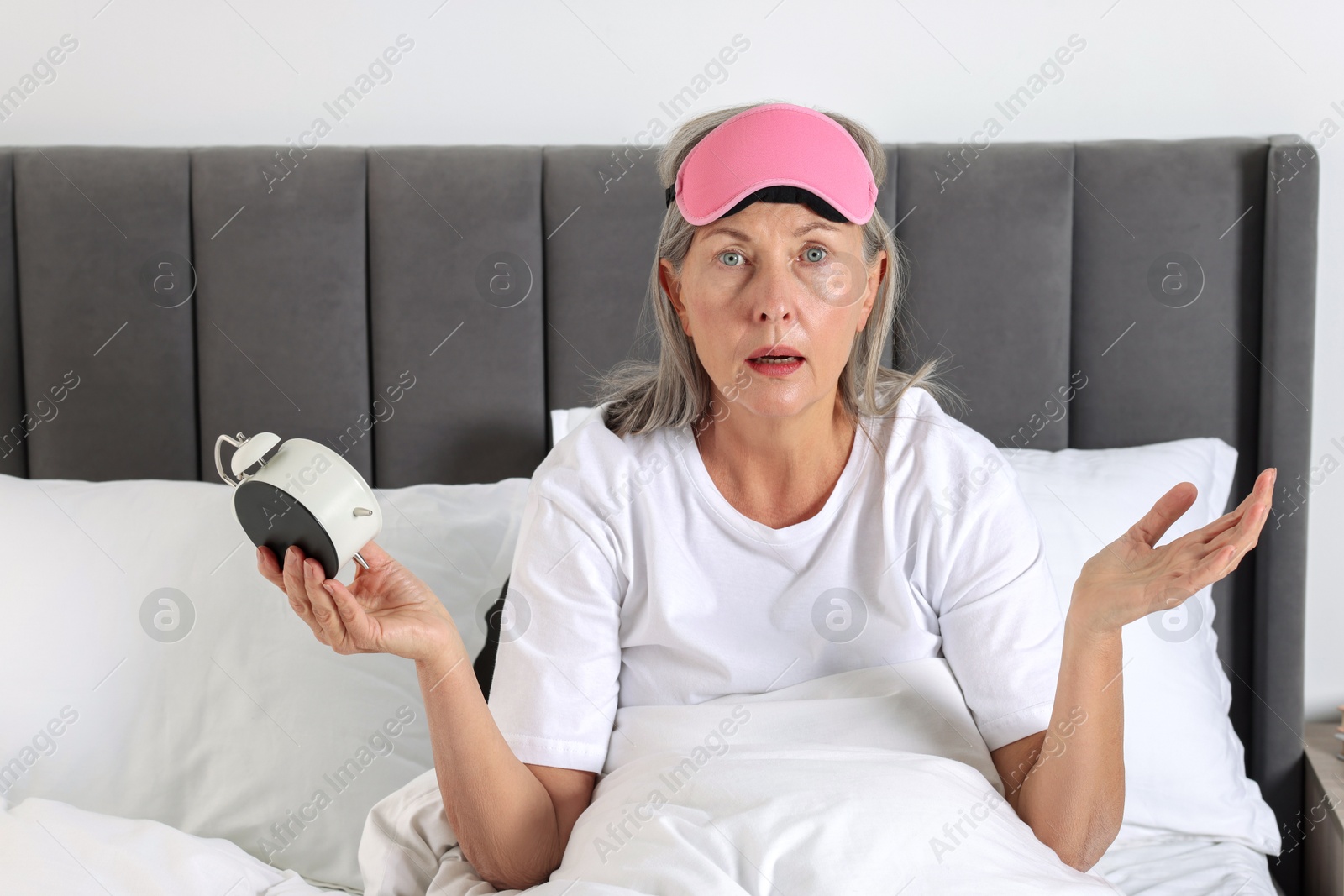 Photo of Overslept woman with alarm clock in bed at home