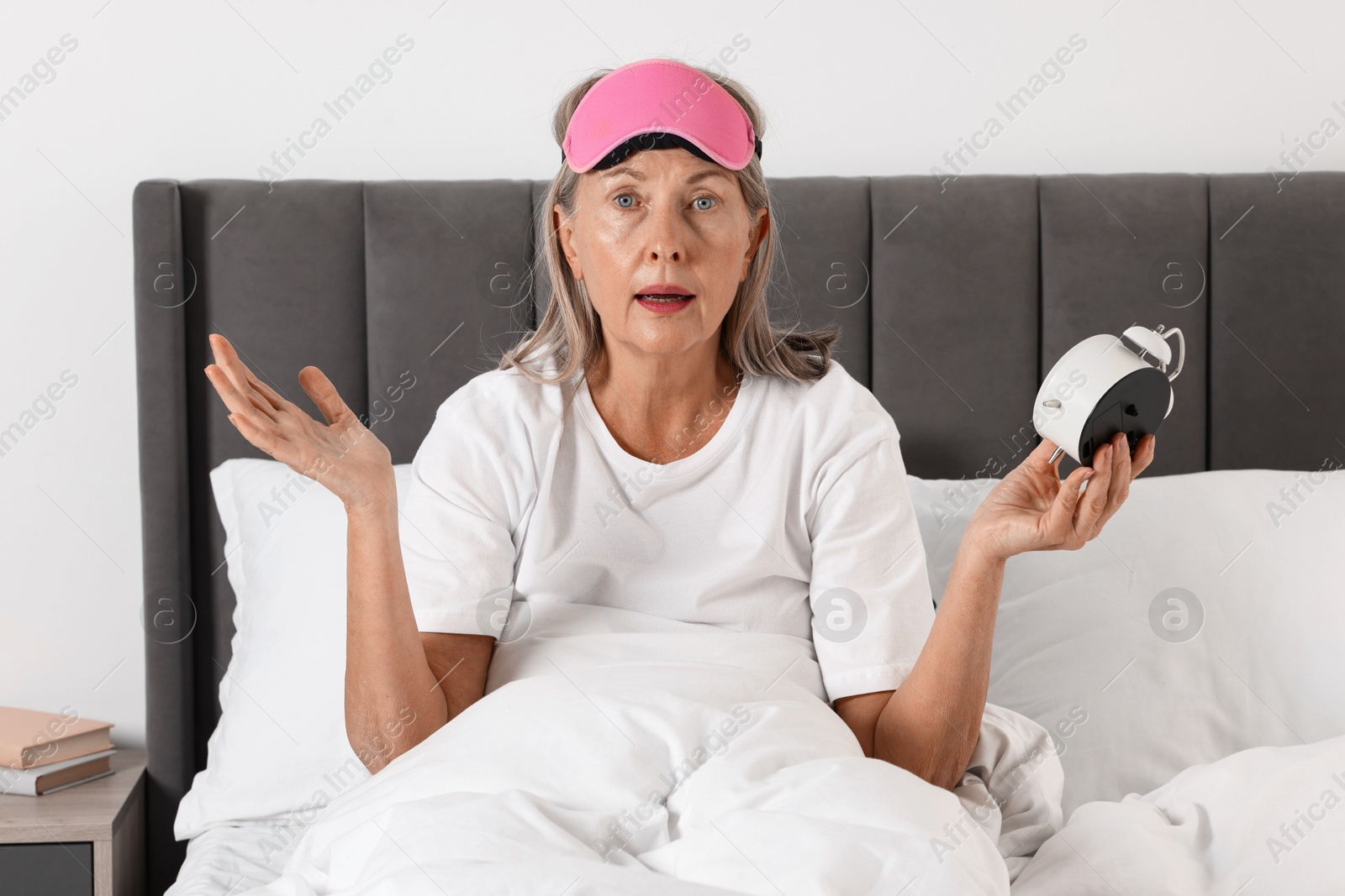 Photo of Overslept woman with alarm clock in bed at home