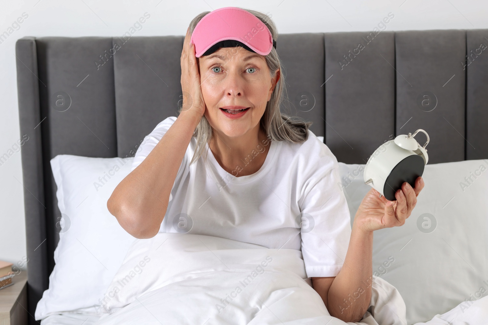 Photo of Overslept woman with alarm clock in bed at home