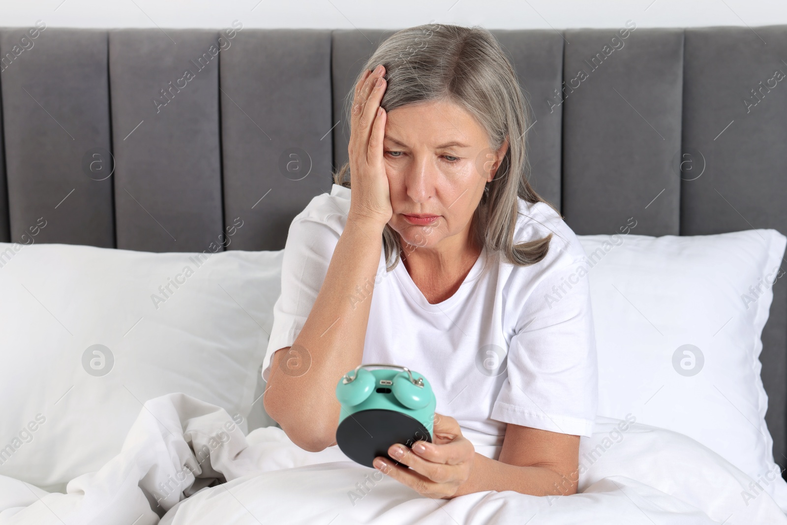 Photo of Overslept woman with alarm clock in bed at home