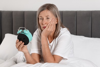 Photo of Overslept woman with alarm clock in bed at home