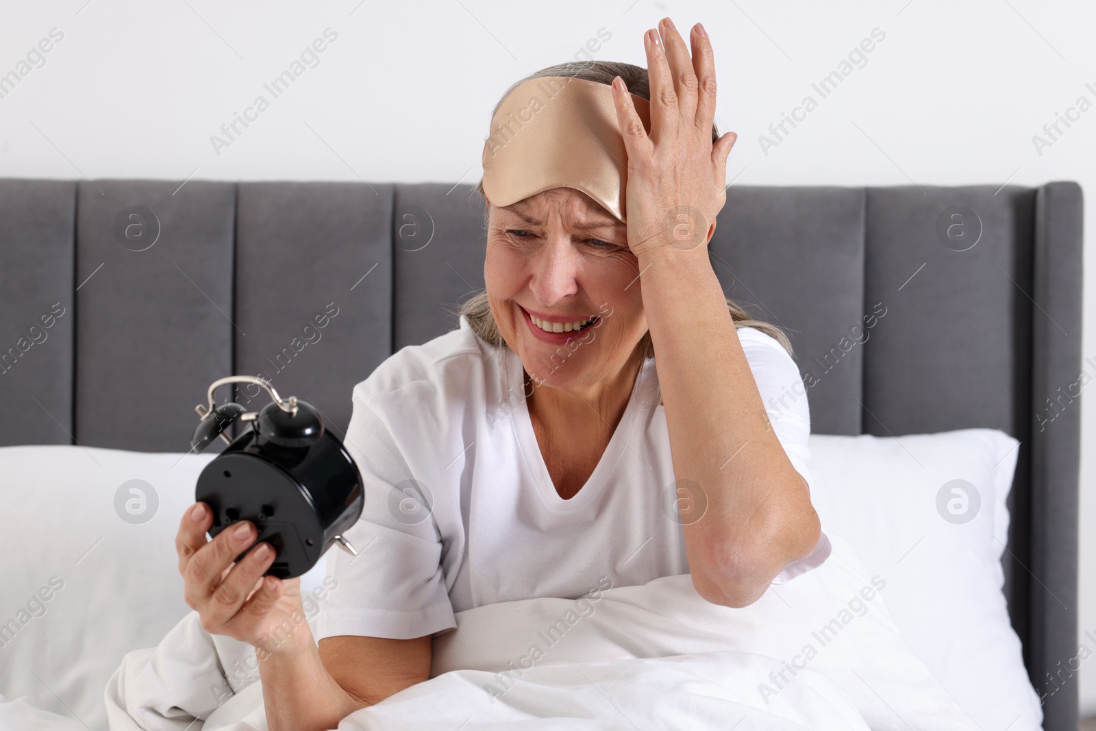 Photo of Overslept woman with alarm clock in bed at home