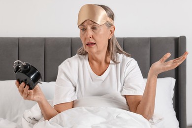 Photo of Overslept woman with alarm clock in bed at home