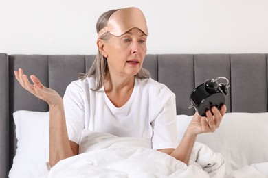 Photo of Overslept woman with alarm clock in bed at home