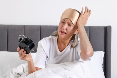 Photo of Overslept woman with alarm clock in bed at home