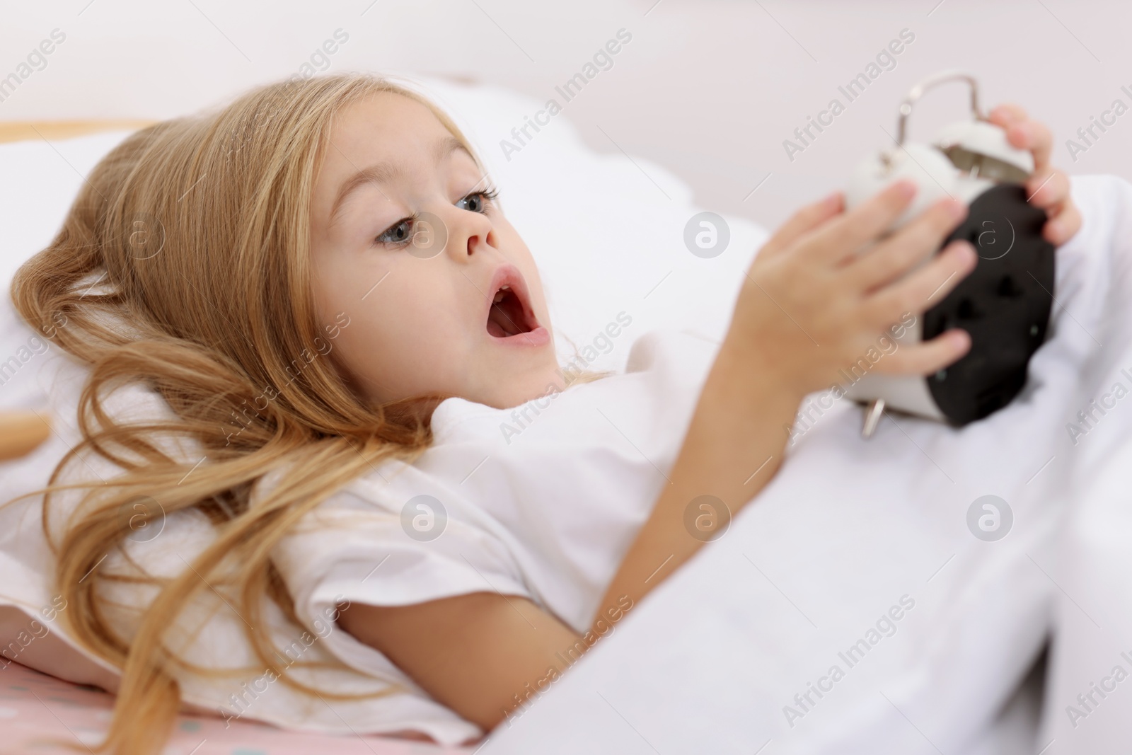 Photo of Overslept girl with alarm clock in bed at home