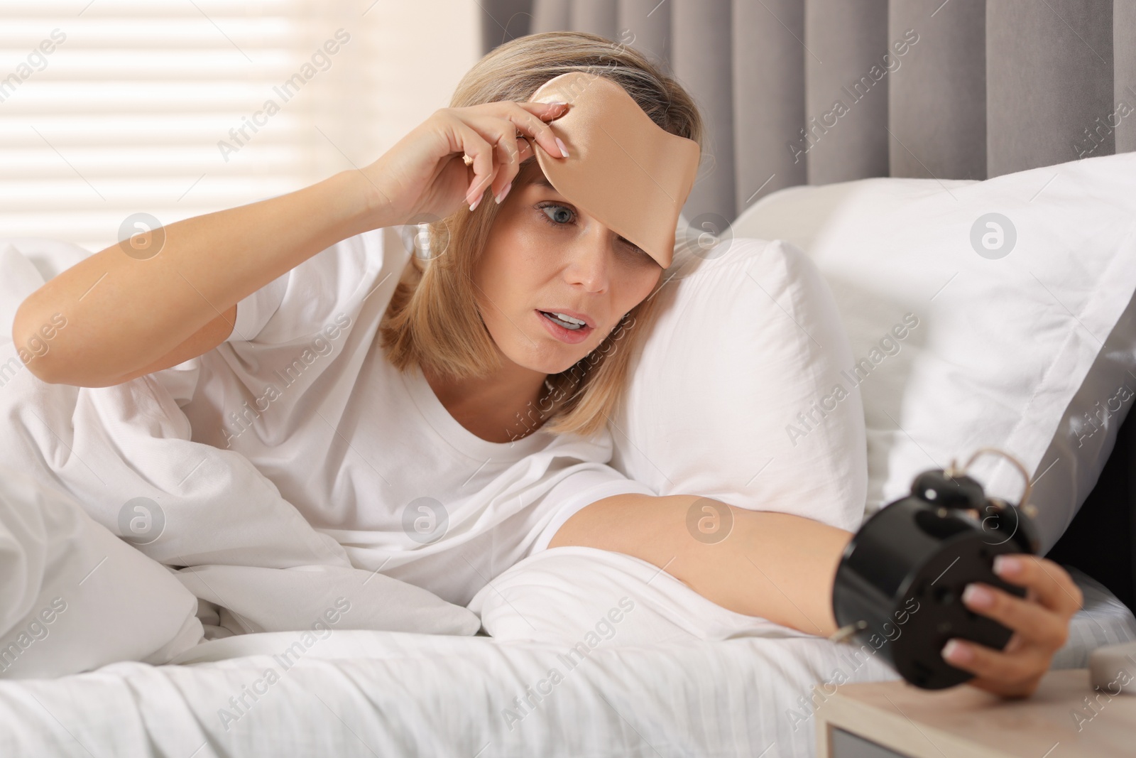 Photo of Overslept woman with alarm clock in bed at home