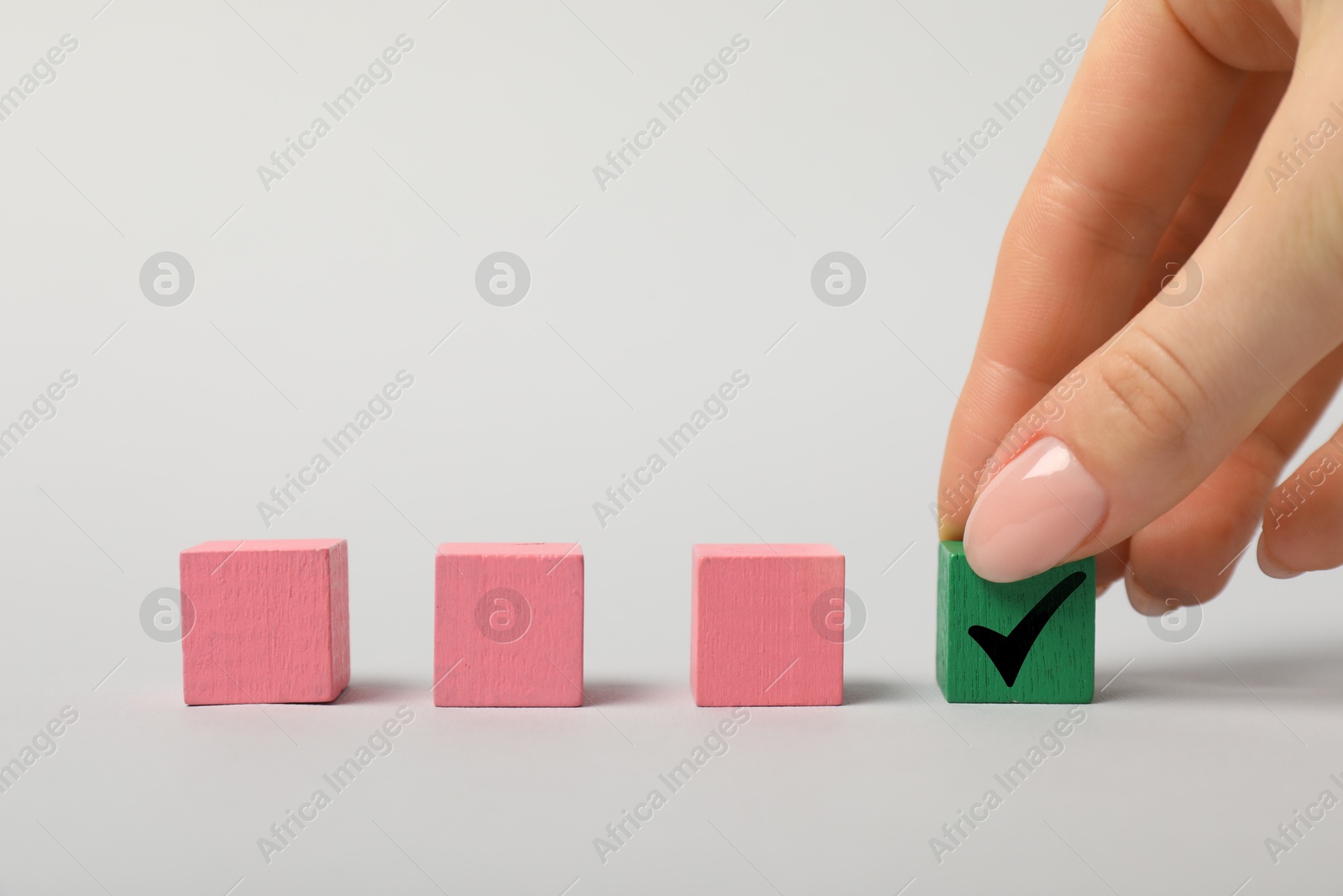 Photo of Woman taking green cube with check mark on white background, closeup