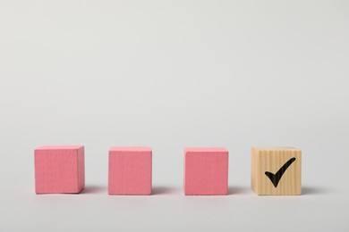 Photo of One wooden cube with check mark among others on white background