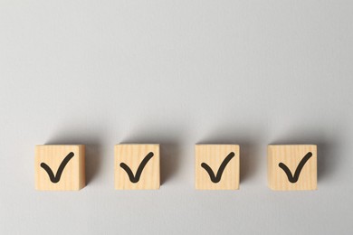 Photo of Wooden cubes with check marks on white background, flat lay