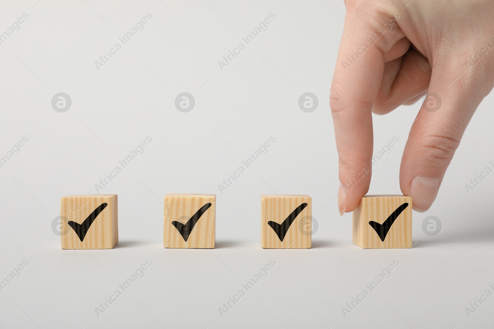 Photo of Woman taking wooden cube with check mark on white background, closeup