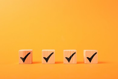 Photo of Wooden cubes with check marks on orange background