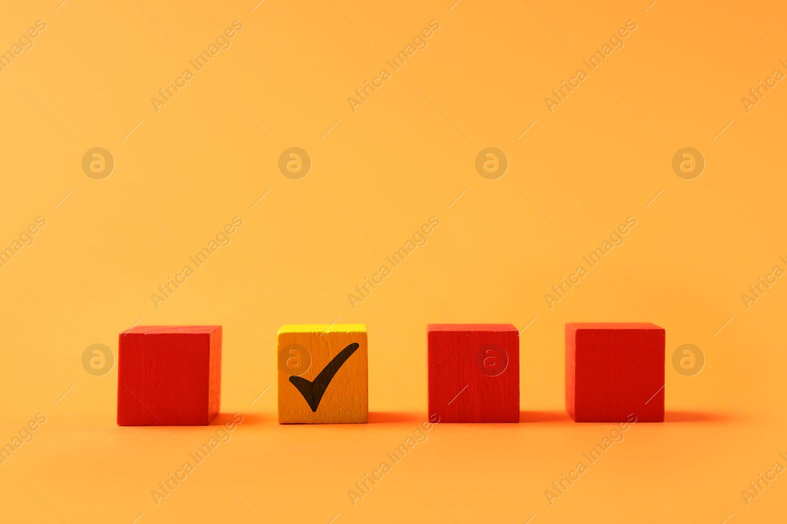 Photo of One color cube with check mark among others on orange background