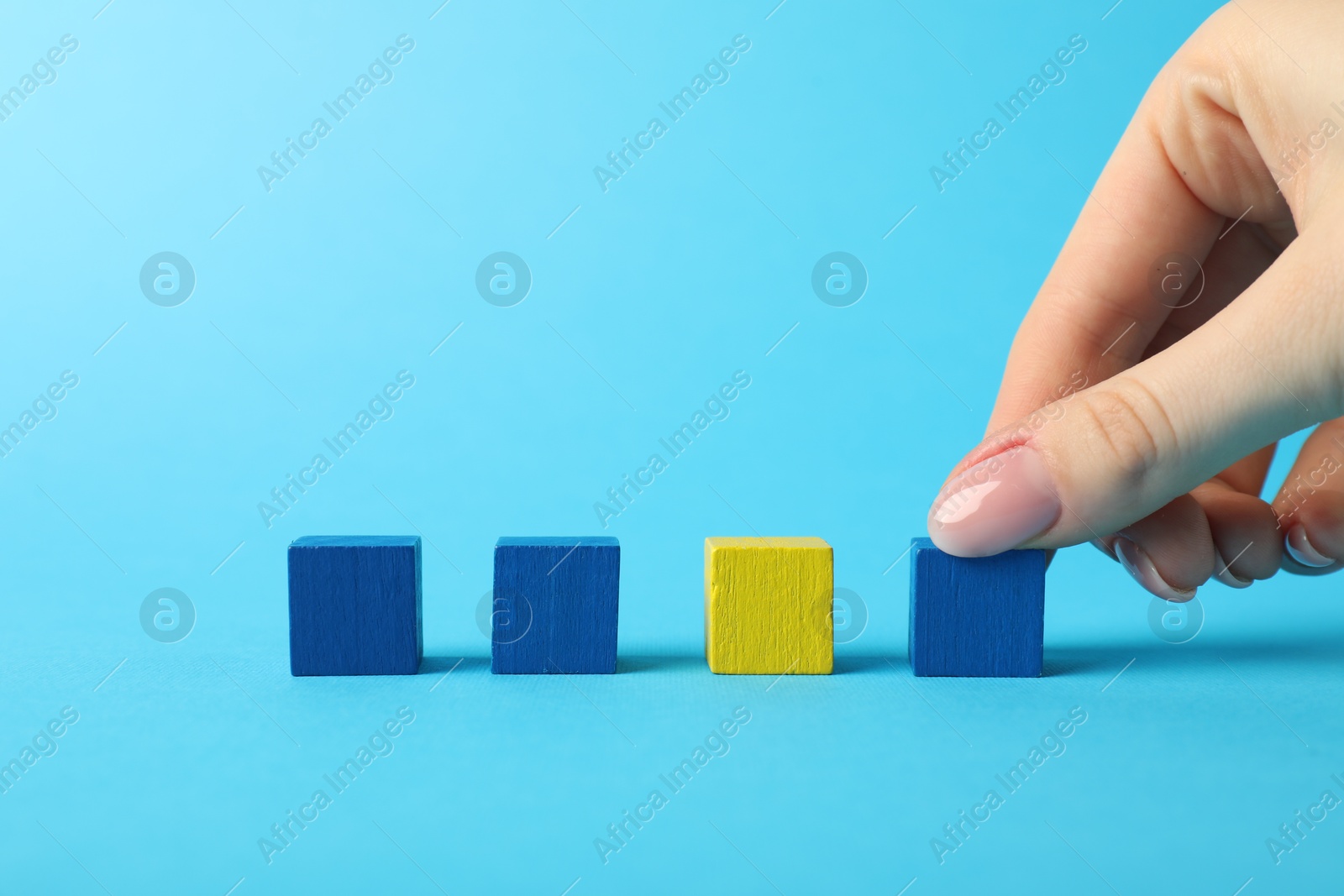 Photo of Woman with colorful cubes on light blue background, closeup