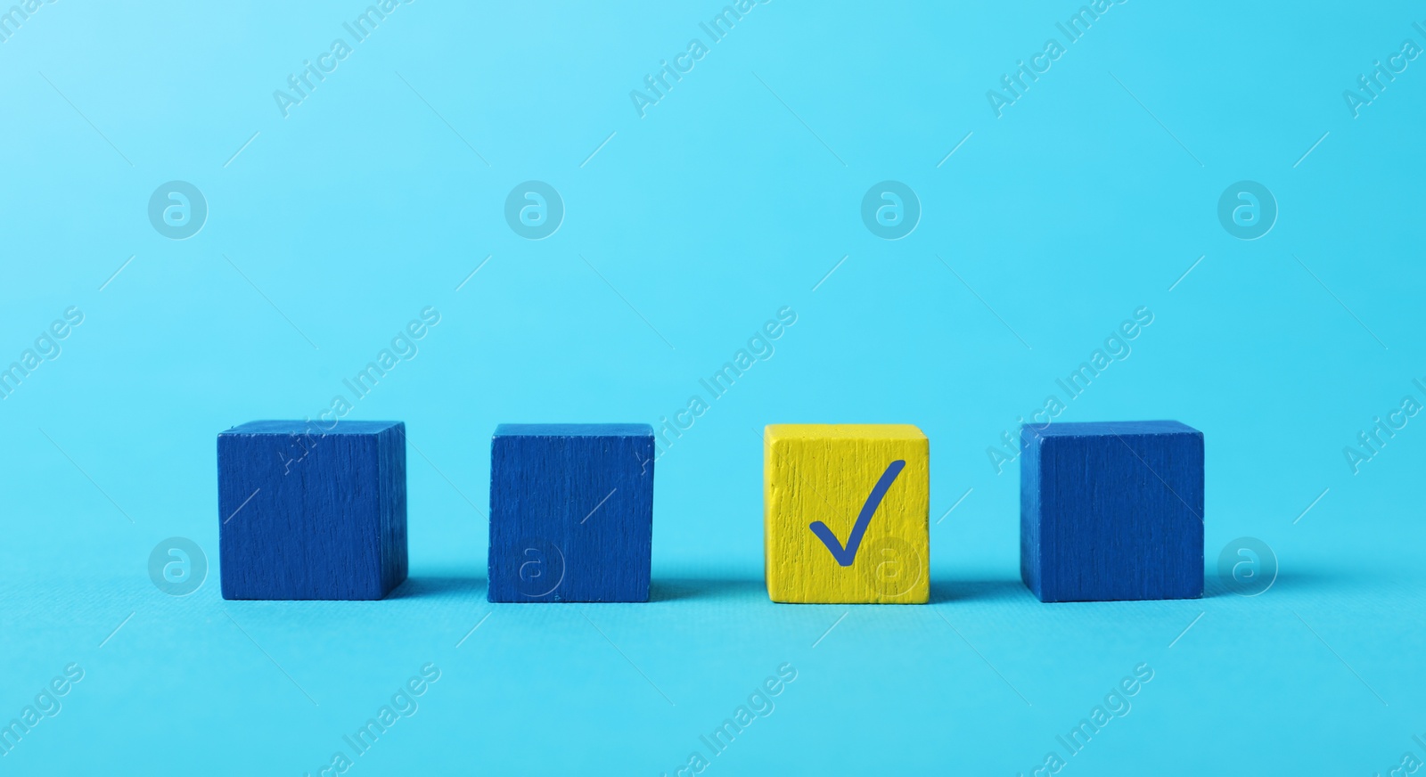 Photo of One yellow cube with check mark among others on light blue background