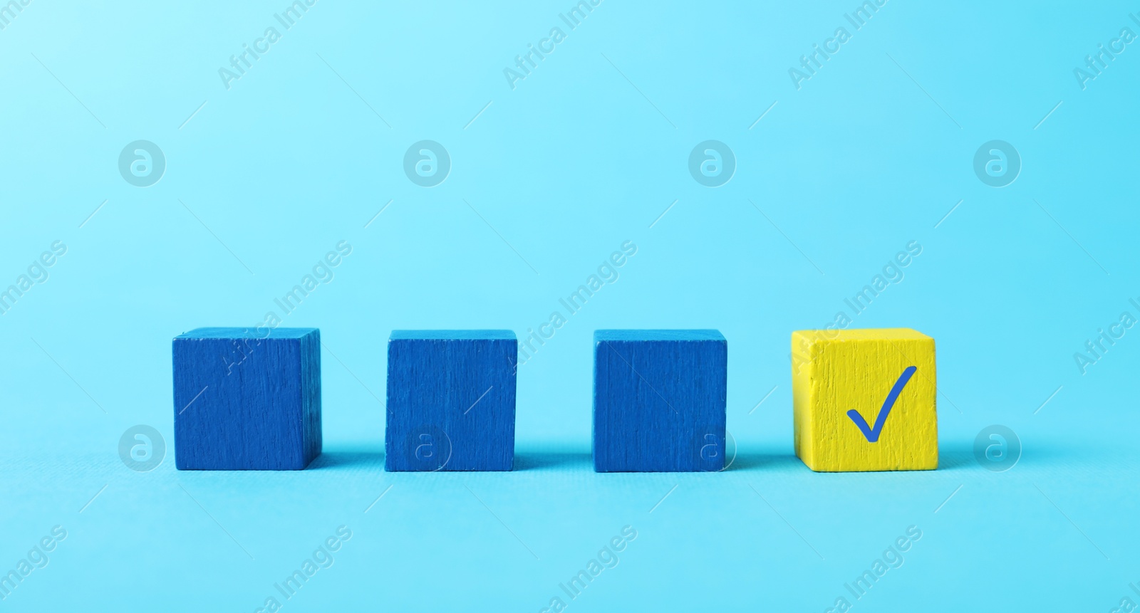 Photo of One yellow cube with check mark among others on light blue background