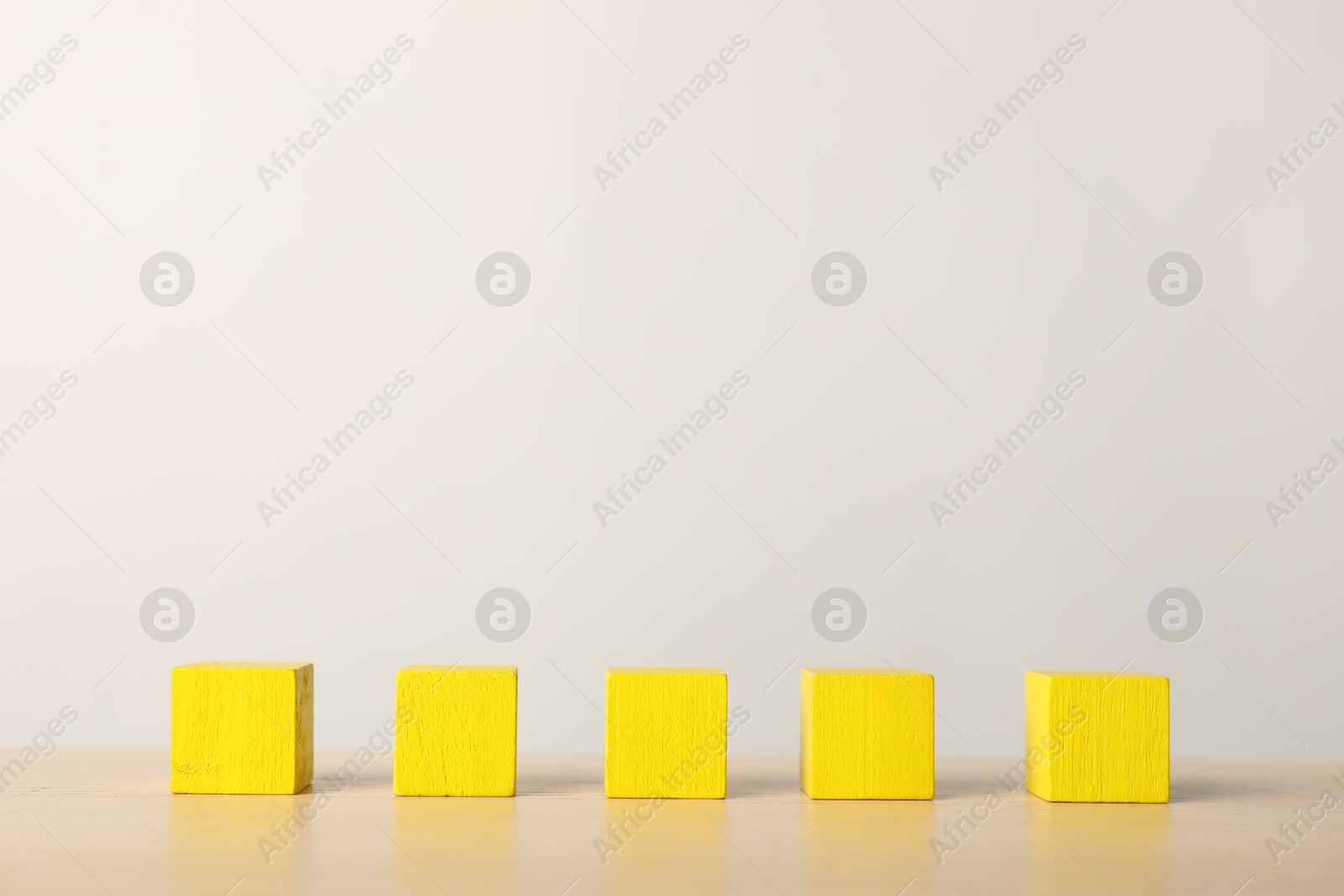 Photo of Many yellow wooden cubes on table, space for text