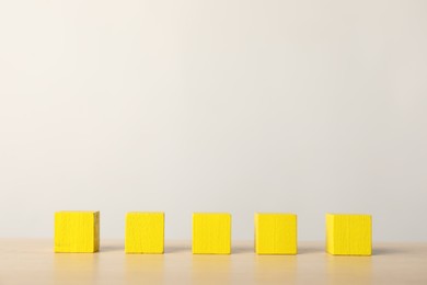 Photo of Many yellow wooden cubes on table, space for text