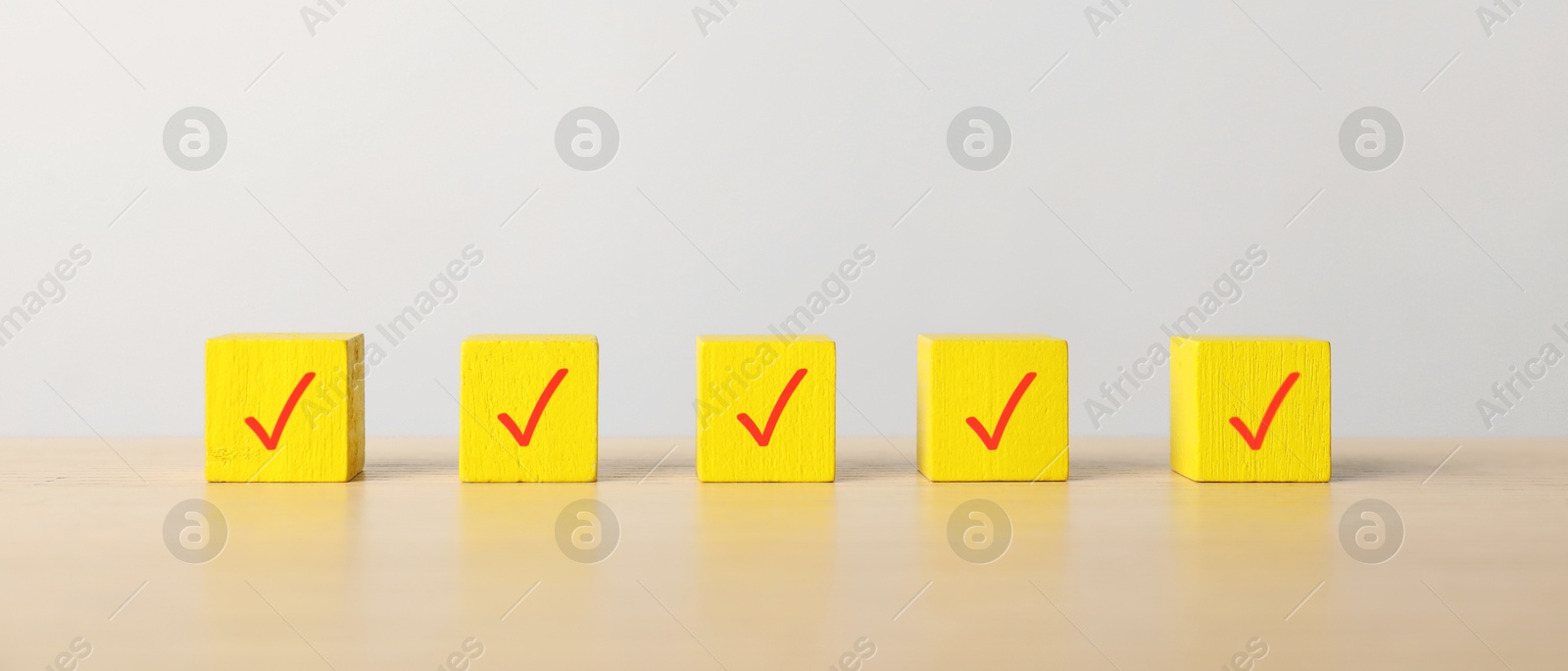 Photo of Yellow cubes with check marks on table