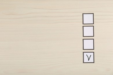 Photo of One checkbox with tick mark among others on wooden table, flat lay. Space for text