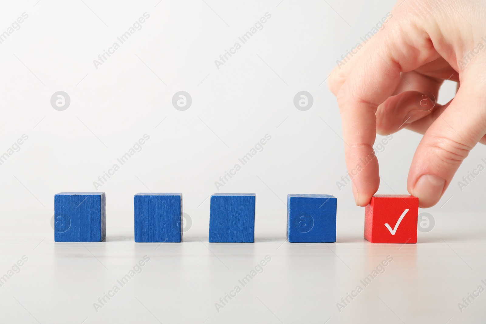 Photo of Woman taking red cube with check mark at table, closeup