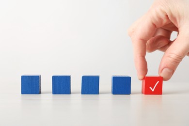 Photo of Woman taking red cube with check mark at table, closeup