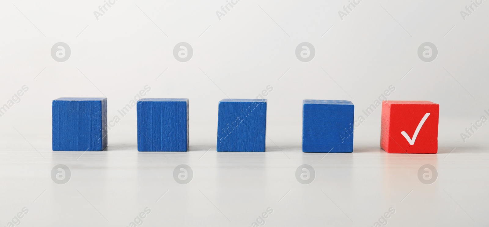 Photo of One red cube with check mark among others on white table