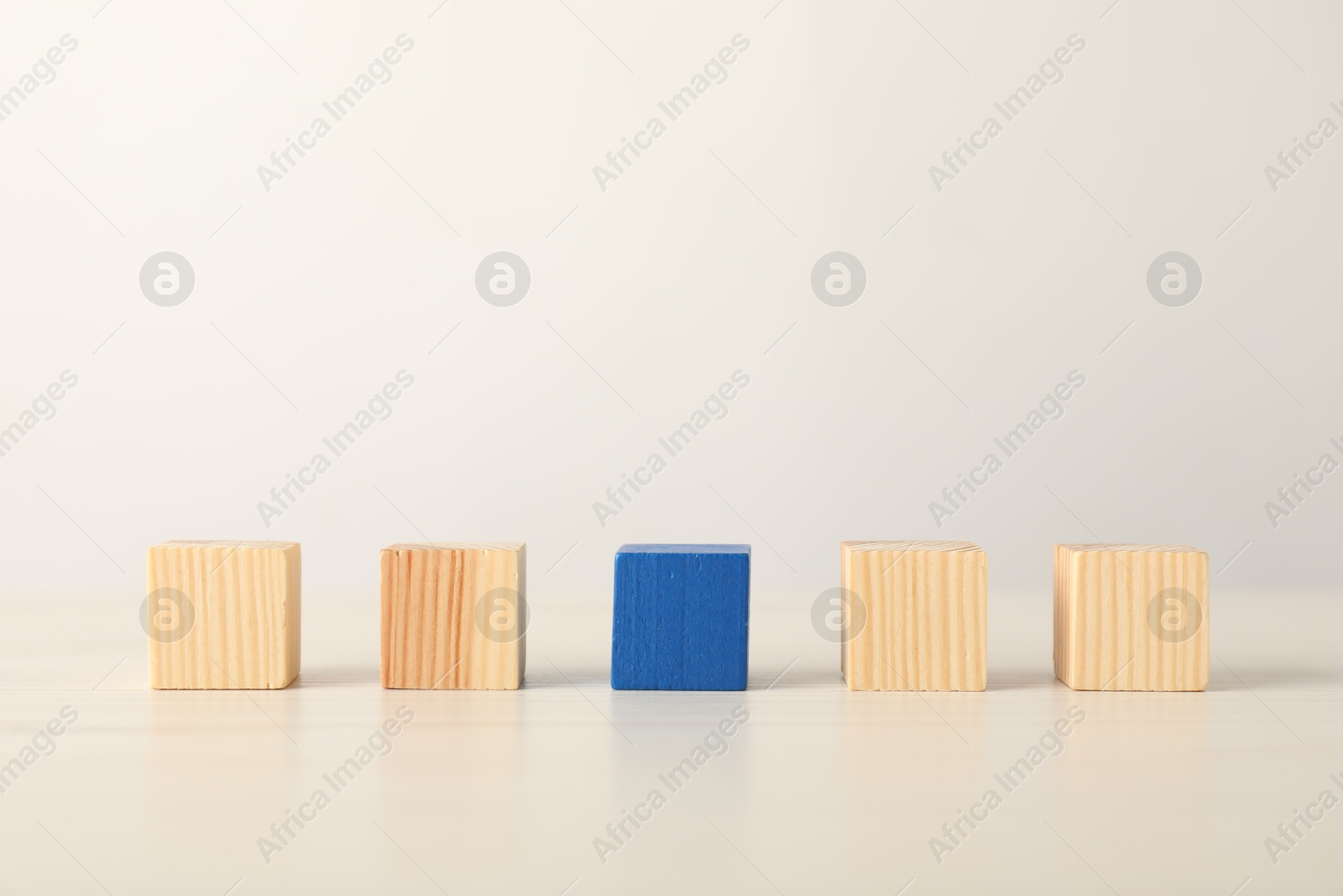 Photo of Many wooden cubes and blue one on table