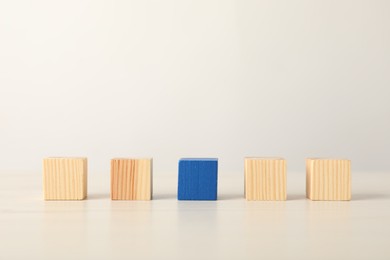 Photo of Many wooden cubes and blue one on table