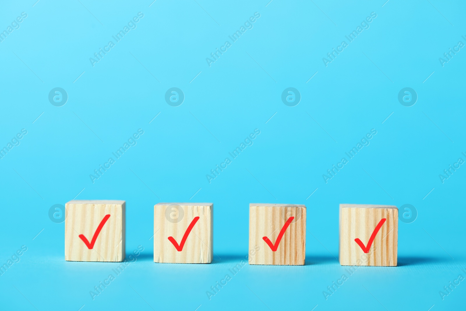 Photo of Wooden cubes with check marks on light blue background