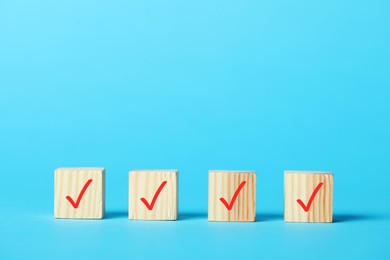 Photo of Wooden cubes with check marks on light blue background