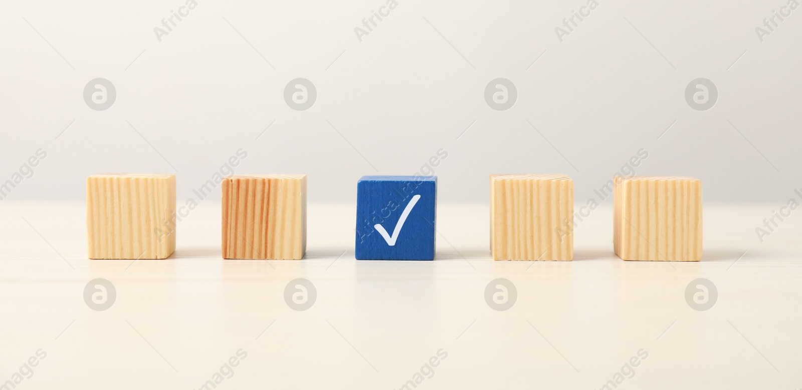 Photo of One blue cube with tick mark among others on light table