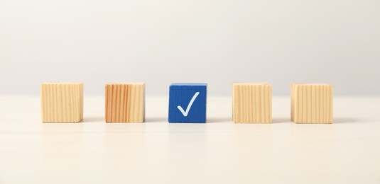 Photo of One blue cube with tick mark among others on light table