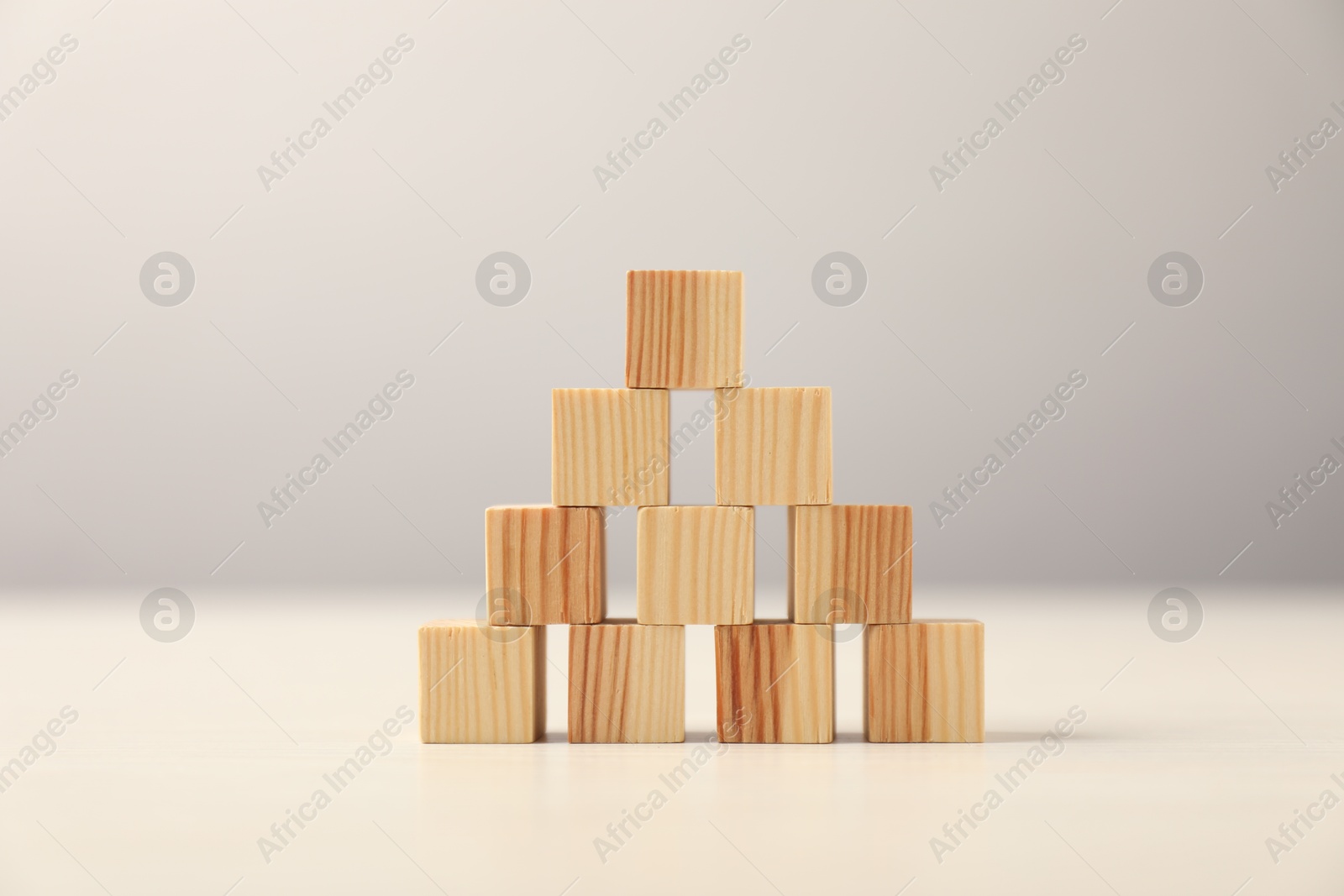 Photo of Pyramid of wooden cubes on table against grey background