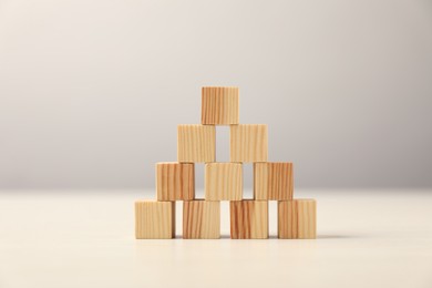 Photo of Pyramid of wooden cubes on table against grey background