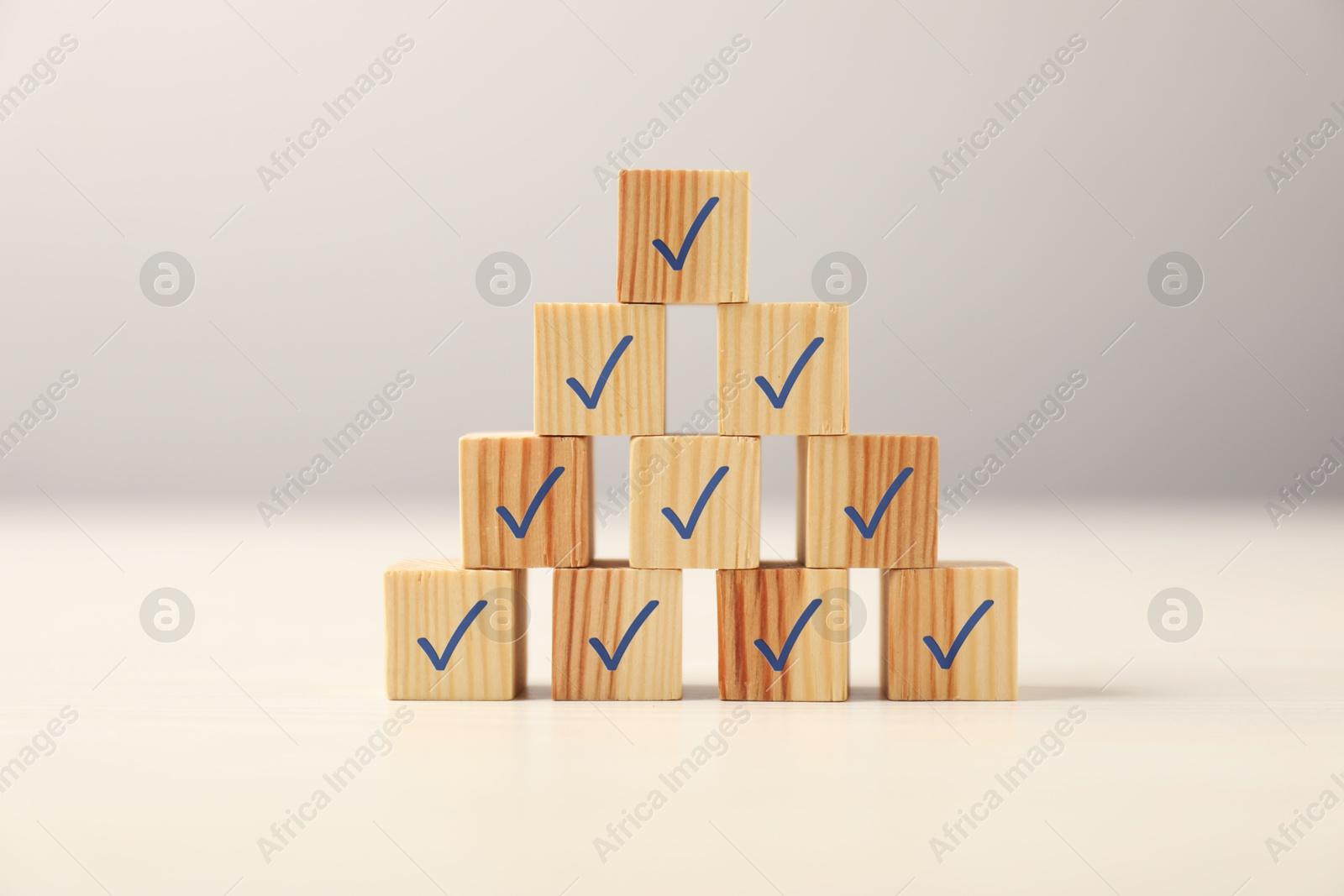 Photo of Pyramid of wooden cubes with check marks on table