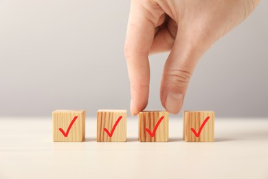 Photo of Woman taking cube with check mark at table, closeup