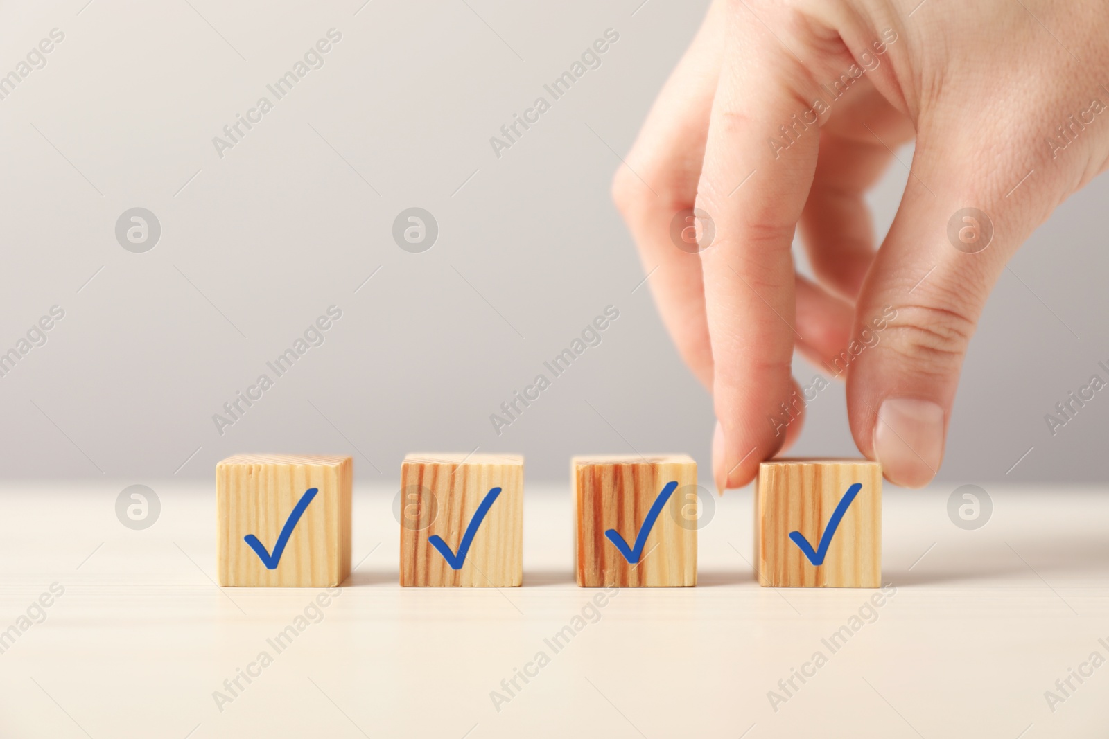 Photo of Woman taking cube with check mark at table, closeup