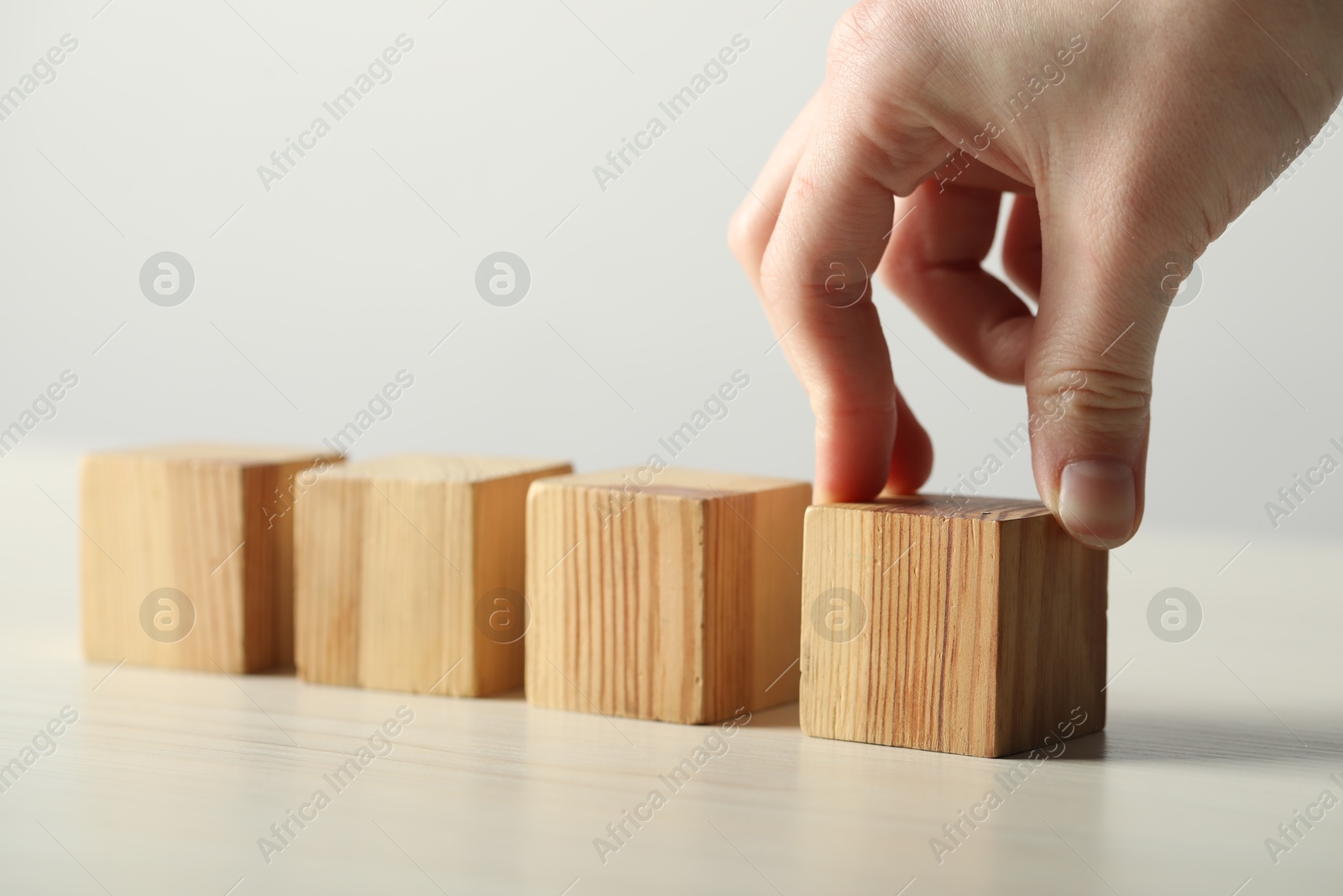 Photo of Woman with wooden cubes at light table, closeup