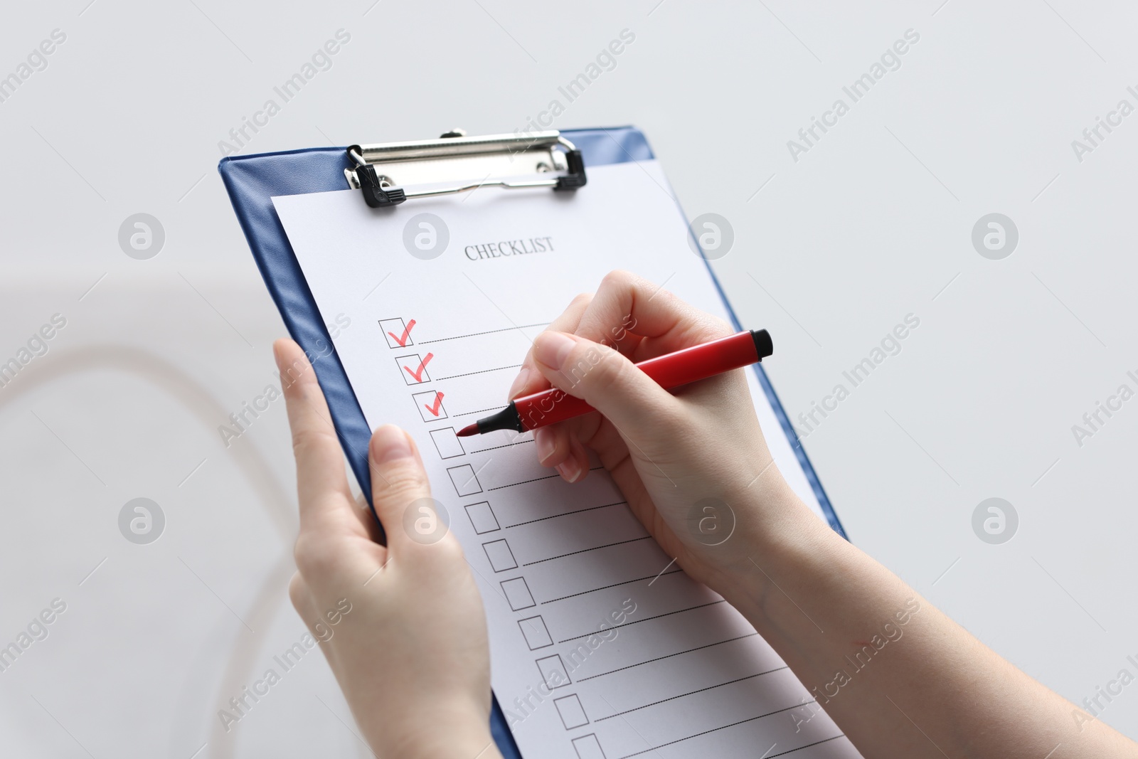 Photo of Woman filling Checklist on blurred background, closeup