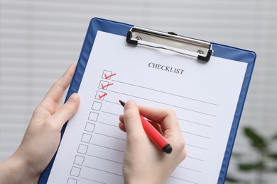 Photo of Woman filling Checklist on blurred background, closeup