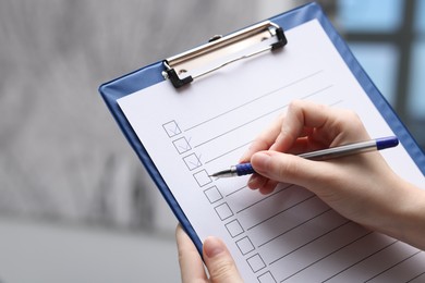 Photo of Woman checking box of paper form indoors, closeup