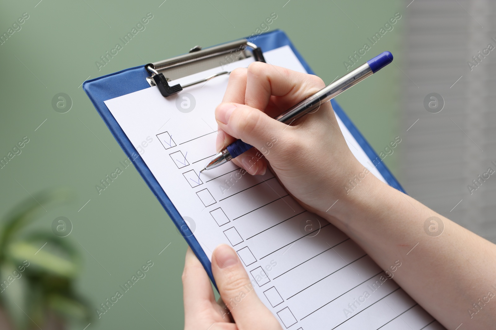 Photo of Woman checking box of paper form indoors, closeup