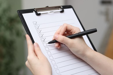 Photo of Woman checking box of paper form indoors, closeup