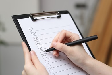 Photo of Woman checking box of paper form indoors, closeup