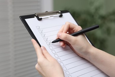 Photo of Woman checking box of paper form indoors, closeup