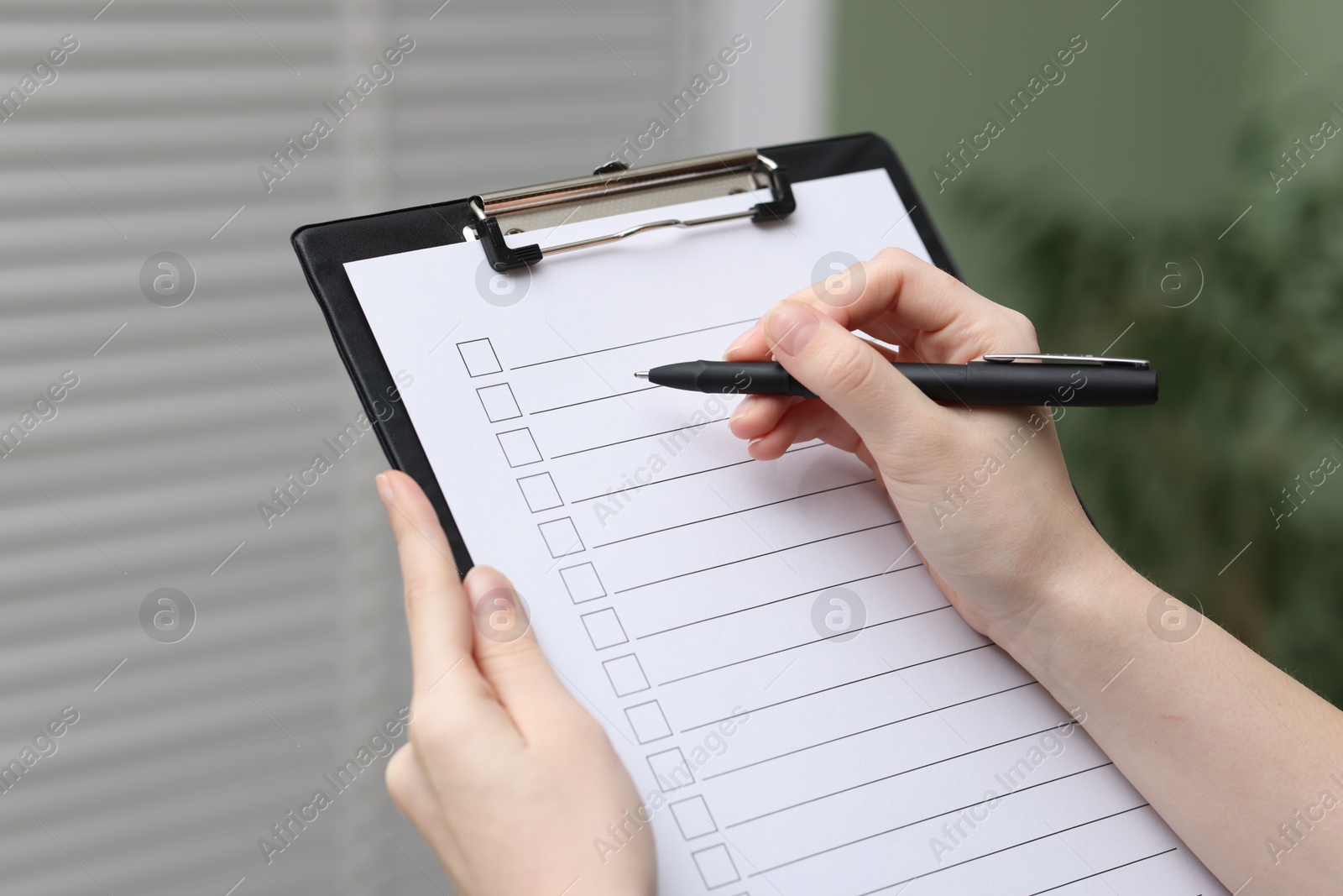 Photo of Woman checking box of paper form indoors, closeup