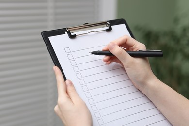 Photo of Woman checking box of paper form indoors, closeup